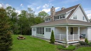 A two-story house with a stone chimney, a porch with white railings, and a small lawn with a picnic table. - Private Family Estate for any Season - Hermitage Club/Inn (West Dover)