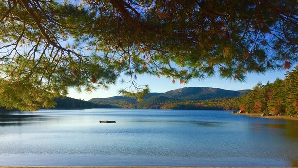 A lake with a wooden dock, surrounded by trees and hills. - Boathouse Cottage. Private Beach. Sunset, Mountain,  Lake Views. Near Acadia NP! (Sullivan)