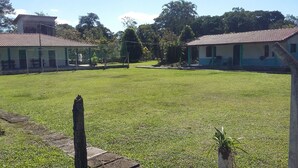 A grassy courtyard with a fenced area, a building with a tiled roof, and a small structure with a door. - BARRETINHO'S FARM. PURE LEISURE!! A MIX OF BEACH AND COUNTRY LIFE, LOTS OF FUN. (Itanhaém)