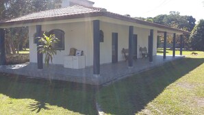 A covered outdoor area with a tiled floor, benches, and a small table with a plant. - BARRETINHO'S FARM. PURE LEISURE!! A MIX OF BEACH AND COUNTRY LIFE, LOTS OF FUN. (Itanhaém)