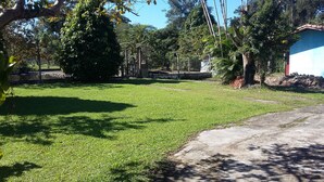 A grassy area with trees and a building in the background. - BARRETINHO'S FARM. PURE LEISURE!! A MIX OF BEACH AND COUNTRY LIFE, LOTS OF FUN. (Itanhaém)