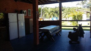 A covered outdoor area with a brick wall, a table with a tablecloth, and a bench. - BARRETINHO'S FARM. PURE LEISURE!! A MIX OF BEACH AND COUNTRY LIFE, LOTS OF FUN. (Itanhaém)