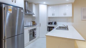 Une cuisine moderne dotée d’appareils électroménagers en acier inoxydable, de meubles blancs et d’un îlot central.