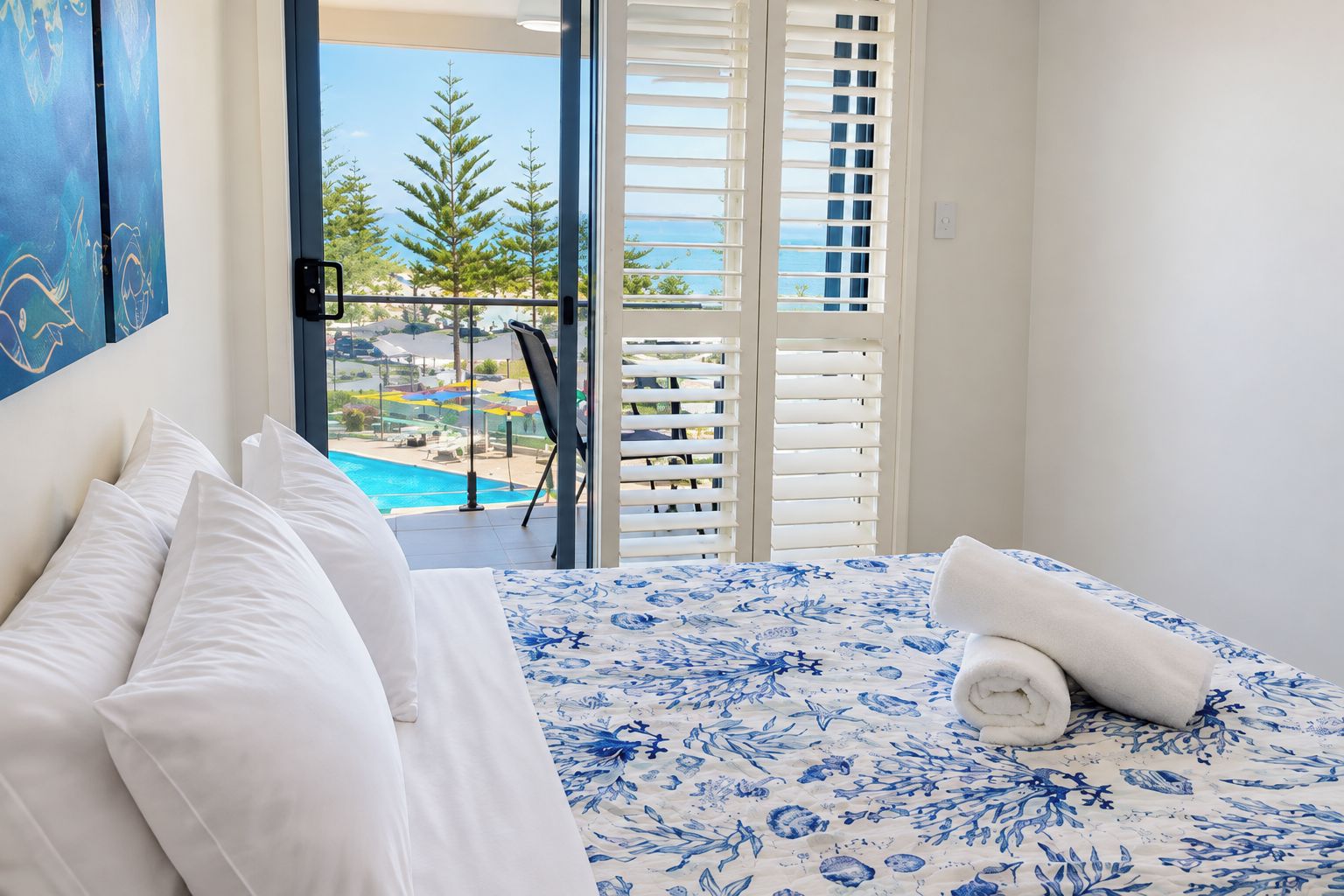 Une chambre à coucher avec un lit, des oreillers blancs et une couvre-lit à motifs floraux bleus.