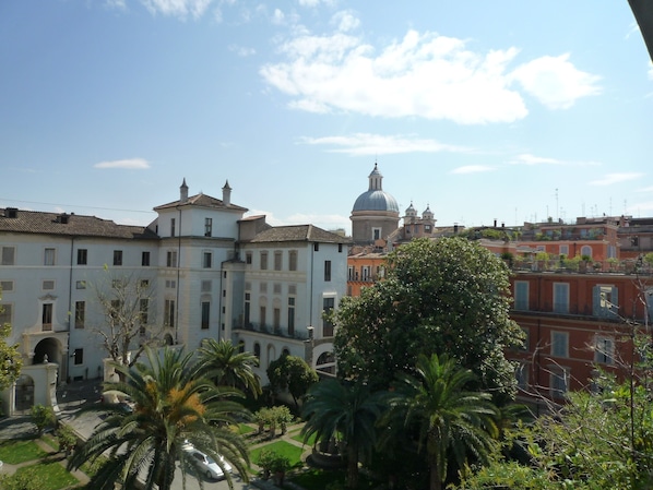 A view of a building with a dome and a courtyard with palm trees.
