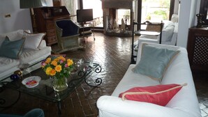 A spacious living room with a fireplace, white sofas, and a glass coffee table with flowers. - luxury penthouse in the heart of Rome with two terrific terraces on the domes (rome)