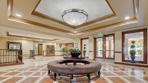 A spacious lobby with a central round table, a chandelier, and a checkered floor pattern. - OVER-SIZED 2 BR PATIO UNIT STEPS TO POOL & COURTYARD!!! (Henderson)