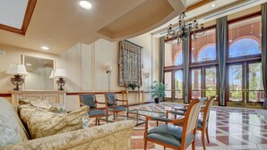 A spacious lobby with a large chandelier, comfortable seating, and a view of the outdoors through large windows. - OVER-SIZED 2 BR PATIO UNIT STEPS TO POOL & COURTYARD!!! (Henderson)