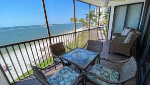 A balcony with wicker furniture, a glass table, and a view of the ocean. - Sanibel Harbour Resort Bay View Tower 236: Beachfront condo overlooking San Carlos Bay. (Fort Myers)