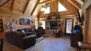 A log cabin interior with a fireplace, wooden ceiling, and a cozy living area with a sofa and coffee table. - Timber Mountain Lodge,  Private Hot Tub .1 Mi to Thunder Ridge; 10 min Branson  (Ridgedale)