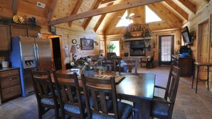 A wooden cabin interior with a dining area, kitchen, and living space. - Timber Mountain Lodge,  Private Hot Tub .1 Mi to Thunder Ridge; 10 min Branson  (Ridgedale)