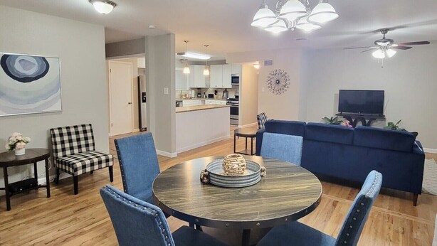 Uma sala de estar moderna com uma mesa redonda, cadeiras azuis, um sofá azul e uma televisão.