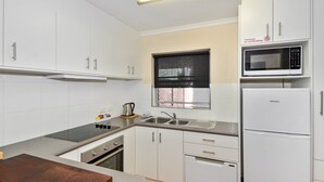 Una cucina moderna con mobili bianchi, un lavello in acciaio inossidabile, un forno a microonde e un frigorifero.
