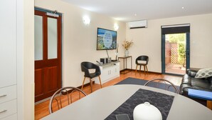Una cucina moderna con una porta in legno, un'area pranzo con tavolo e sedie, e un soggiorno con divano e televisore.