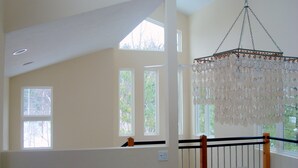 Una habitación con ventanas amplias, una araña y una escalera.