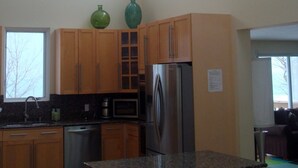 Una cocina moderna con armarios de madera, un refrigerador de acero inoxidable y una encimera de granito.