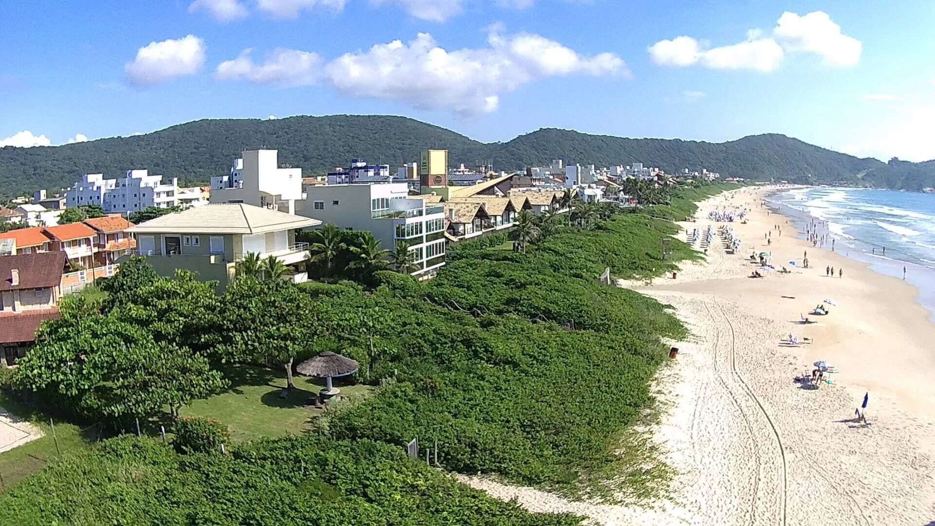 Eine Küstenstadt mit Sandstrand, üppiger Vegetation und verschiedenen Gebäuden, darunter Wohn- und Geschäftsgebäude.