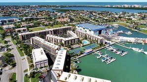 A marina with boats, a tennis court, and a hotel with multiple buildings and a parking lot. - Great Unit On Marco River (marco island)