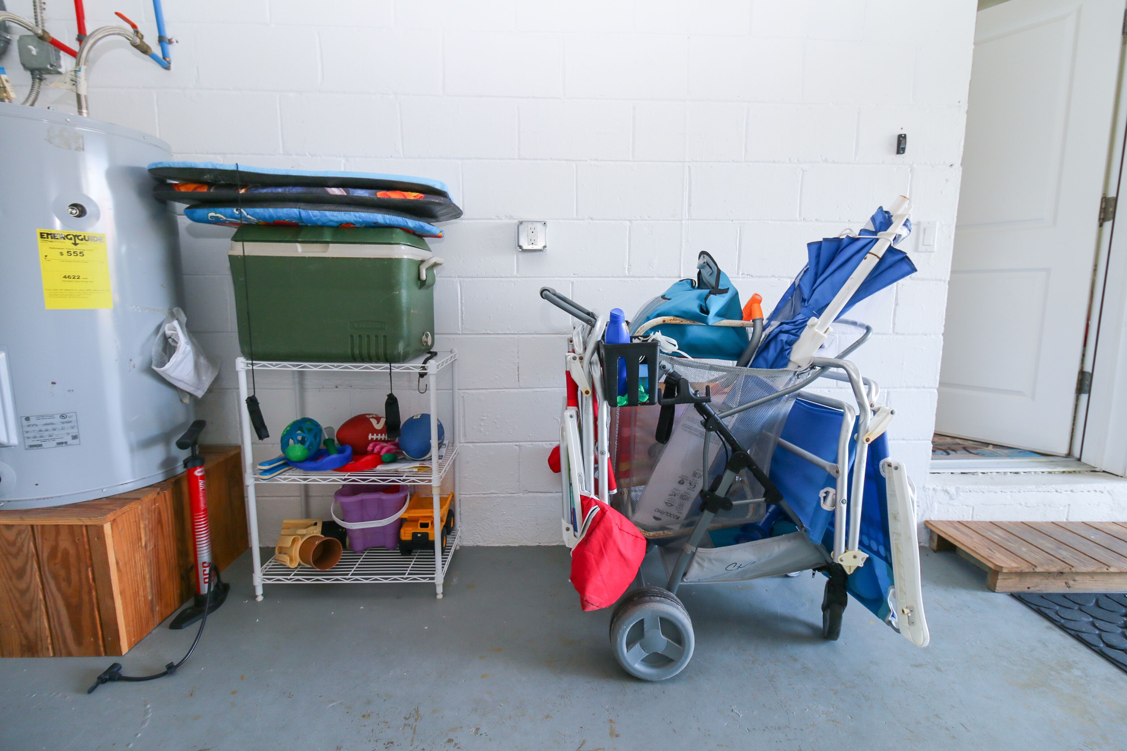 A utility room with a water heater, shelves with cleaning supplies, and a cart with cleaning equipment.