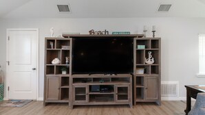 A living room with a wooden entertainment center, a white door, and a window with blinds.