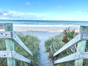 A wooden pathway leading to a beach with a clear view of the ocean.
