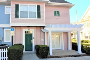 A two-story building with a green door and a white porch. - Cute and Cozy Venetian Bay Townhome - VB007 (Kissimmee)