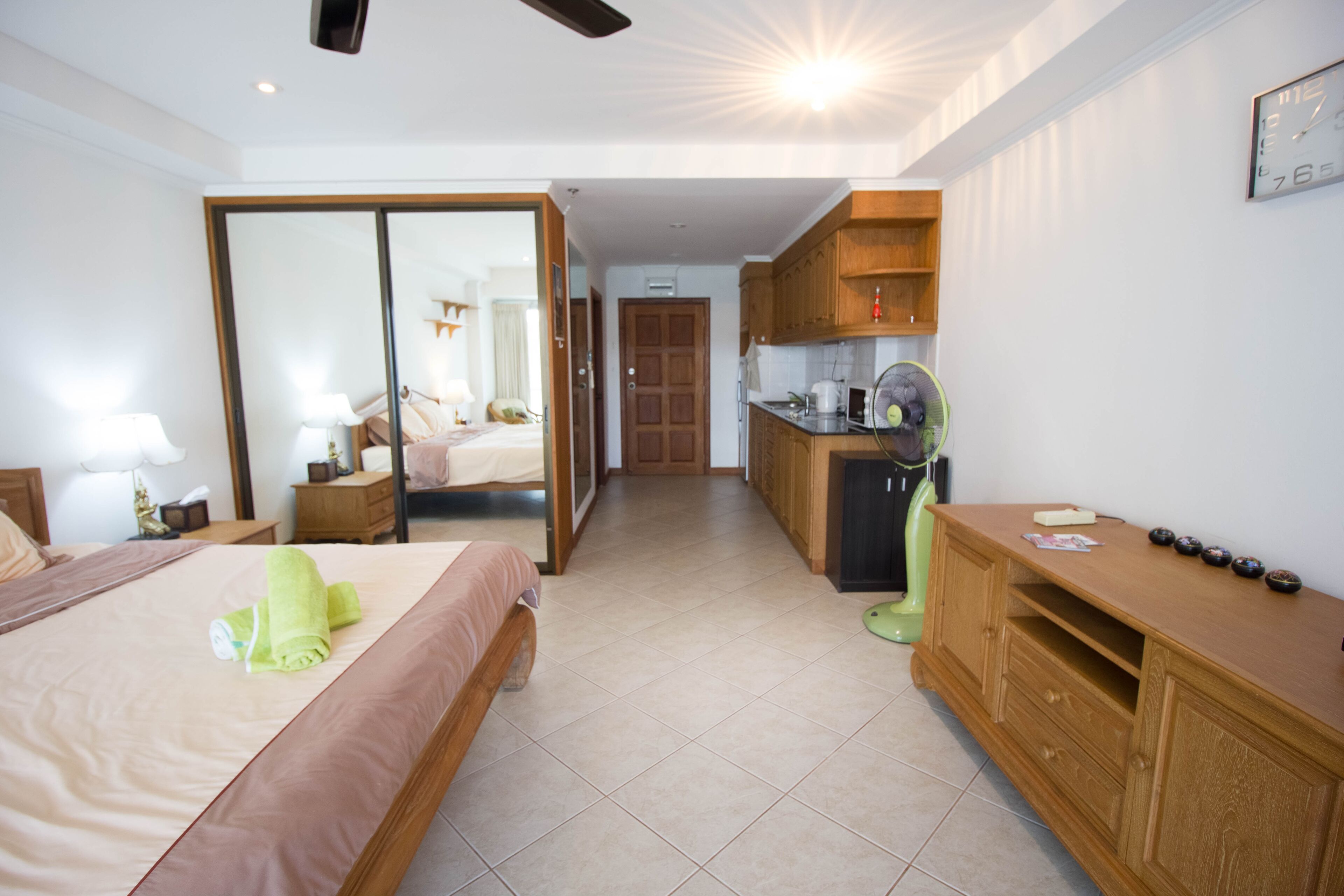 Habitación de hotel con cama, escritorio, kitchenette y puerta corrediza que da al baño.