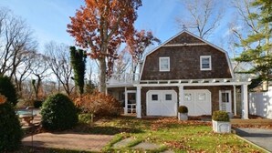 Une maison à deux étages avec un garage, entourée d’un jardin agrémenté d’un chemin en pierre.