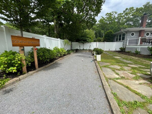 A gravel path leading to a white fence with a wooden sign displaying numbers. - Beach, Pool, Wine, Shopping! (Mattituck)