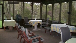 A covered outdoor seating area with tables and chairs, surrounded by trees. - It's a place that attracts happiness. (Lexington)
