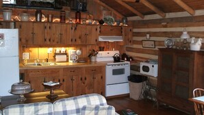 A rustic kitchen with wooden cabinets, a stove, and a microwave. - It's a place that attracts happiness. (Lexington)