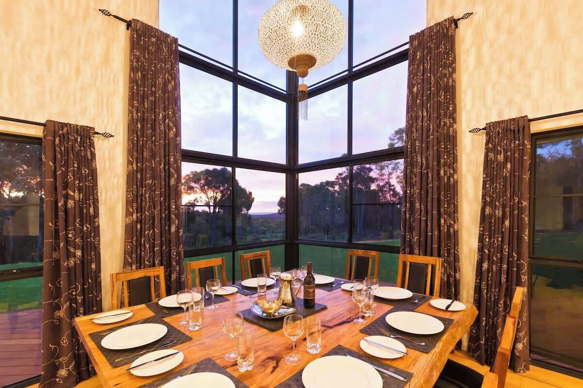 Mesa de comedor para seis personas con vistas al exterior a través de amplias ventanas.