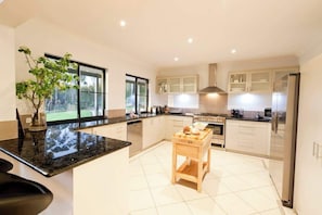 A modern kitchen with a central island, stainless steel appliances, and a view of the outdoors.