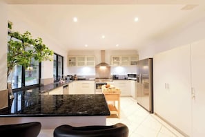 A modern kitchen with a central island, built-in appliances, and a view of the outdoors.