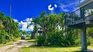 A rural road with a car parked on the side, surrounded by lush greenery and a clear blue sky. - Cudjoe Cottages, swimming pool, just 20 miles from Key West (Cudjoe Key)