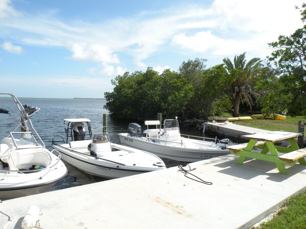 A marina with two boats docked, a picnic table, and a view of the water and trees. - Cudjoe Cottages, swimming pool, just 20 miles from Key West (Cudjoe Key)