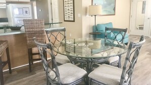 A dining area with a glass table surrounded by wicker chairs, a blue sofa, and a framed fish picture on the wall. - Cudjoe Cottages, swimming pool, just 20 miles from Key West (Cudjoe Key)