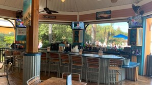 Eine Bar mit verschiedenen Sitzmöglichkeiten, einer Theke voller Flaschen und einem Schild mit der Aufschrift 'Happy Hour'.