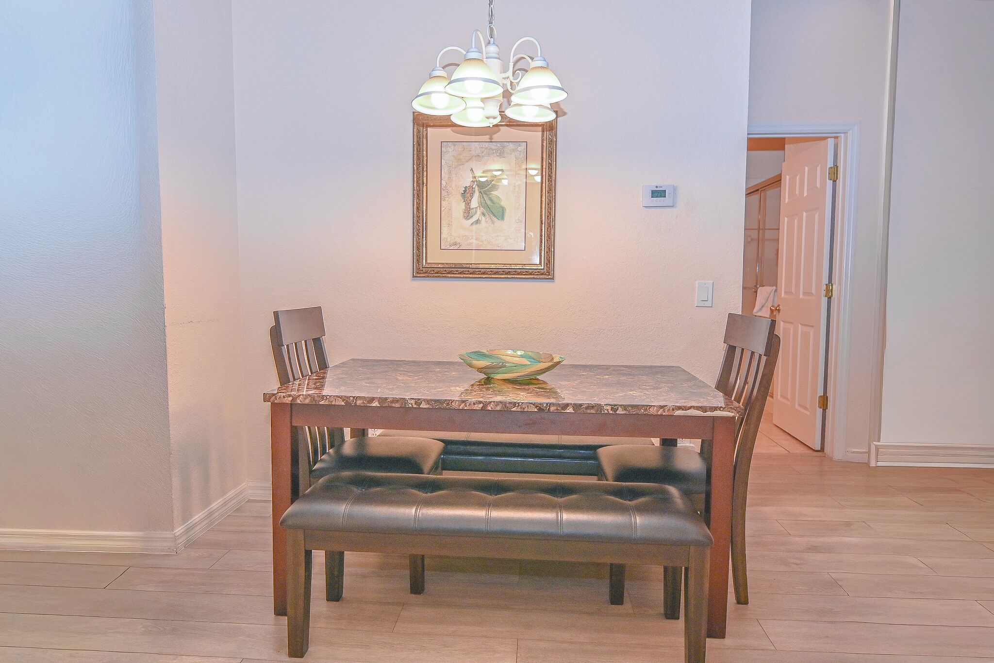 Un espace repas comprenant une table en bois, un banc rembourré et un luminaire suspendu.