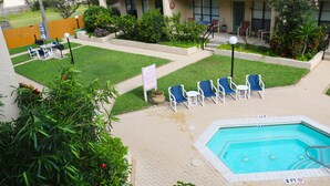 Un área de piscina con un cartel de 3 pies de profundidad, rodeada de sillas y un pequeño césped.
