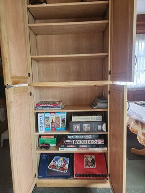 A wooden bookshelf with various board games and puzzles.