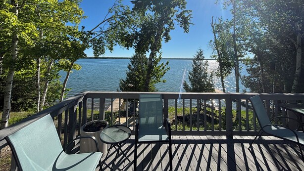 Une terrasse en bois, aménagée avec du mobilier d’extérieur, donnant sur une étendue d’eau.