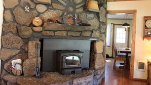 Una chimenea de piedra con un horno de leña, rodeada de paredes y estantes con diversos objetos.