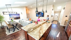 Una cocina moderna con encimera de granito, armarios de madera y un comedor con sofá y mesa.