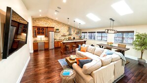Un espacio habitable amplio con un sofá grande, una mesa de comedor y una cocina al fondo.
