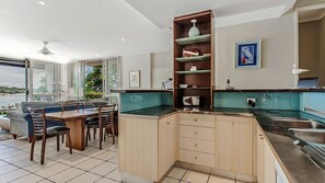 A modern kitchen with a central island, wooden cabinets, and a dining area with a sofa and chairs.