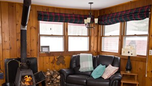 Una habitación acogedora con chimenea, sofá de cuero y cortinas escocesas.