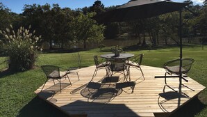 Eine Terrasse im Freien mit einem runden Tisch und Stühlen, umgeben von einer Holzterrasse.