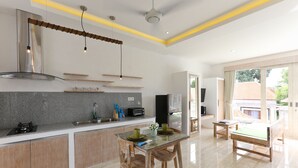 Een moderne keuken met een centraal eiland, ingebouwde apparatuur en een eethoek met een glazen tafel en houten stoelen.