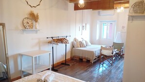 A cozy room with a bed, a small table, a chair, and a clothing rack.